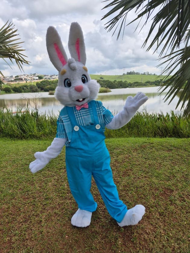 coelho azul mascote em frente ao lago com gravata borboleta na cor rosa