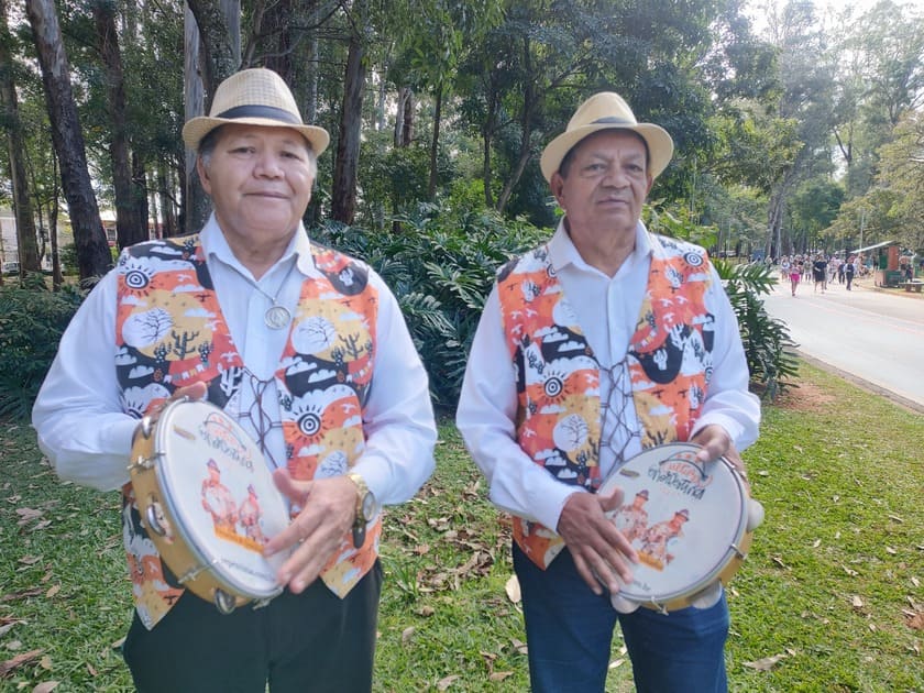 Repentistas com pandeiro realizando cantoria improvisada em evento ao ar livre