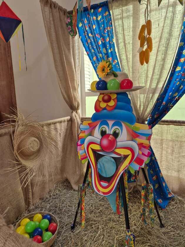 Brincadeira boca do palhaço para festa junina com estrutura temática e bolas para jogo