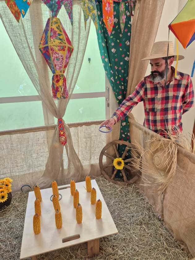 Personagem caipira brincando de jogo de argolas em festa junina com decoração temática