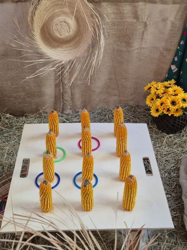 Jogo de argolas com pinos em milho em mesa decorada para festa junina