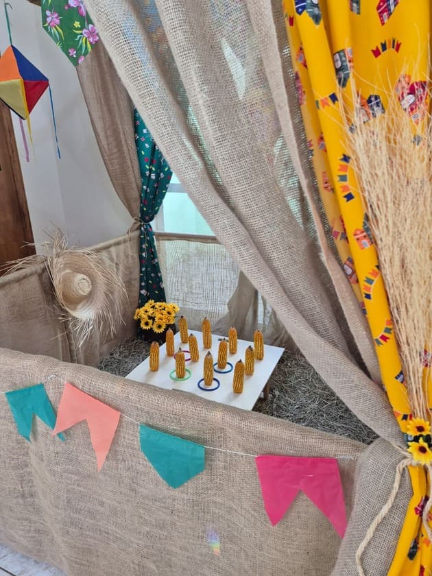 Jogo de argolas com pinos de madeira em mesa decorada para festa junina