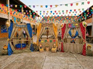 Barracas de brincadeiras para festa junina com pescaria, jogo de argolas e boca do palhaço montadas em evento com decoração típica e bandeirinhas coloridas