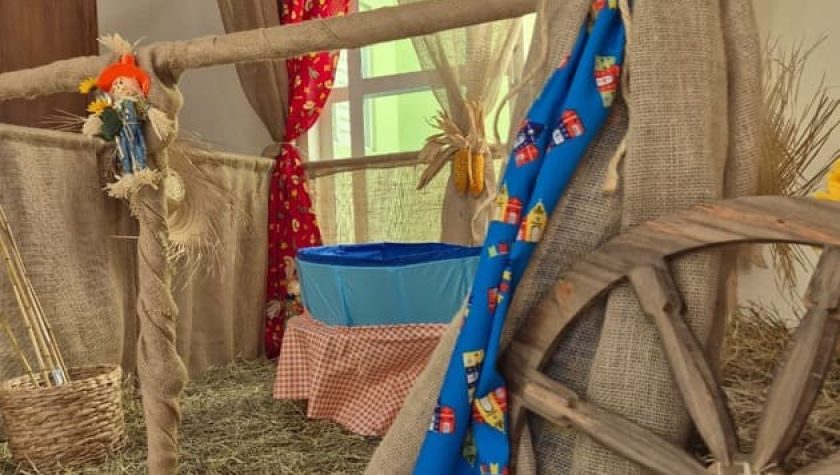 Decoração de festa junina com roda de carroça, tecido rústico e bandeirinhas coloridas
